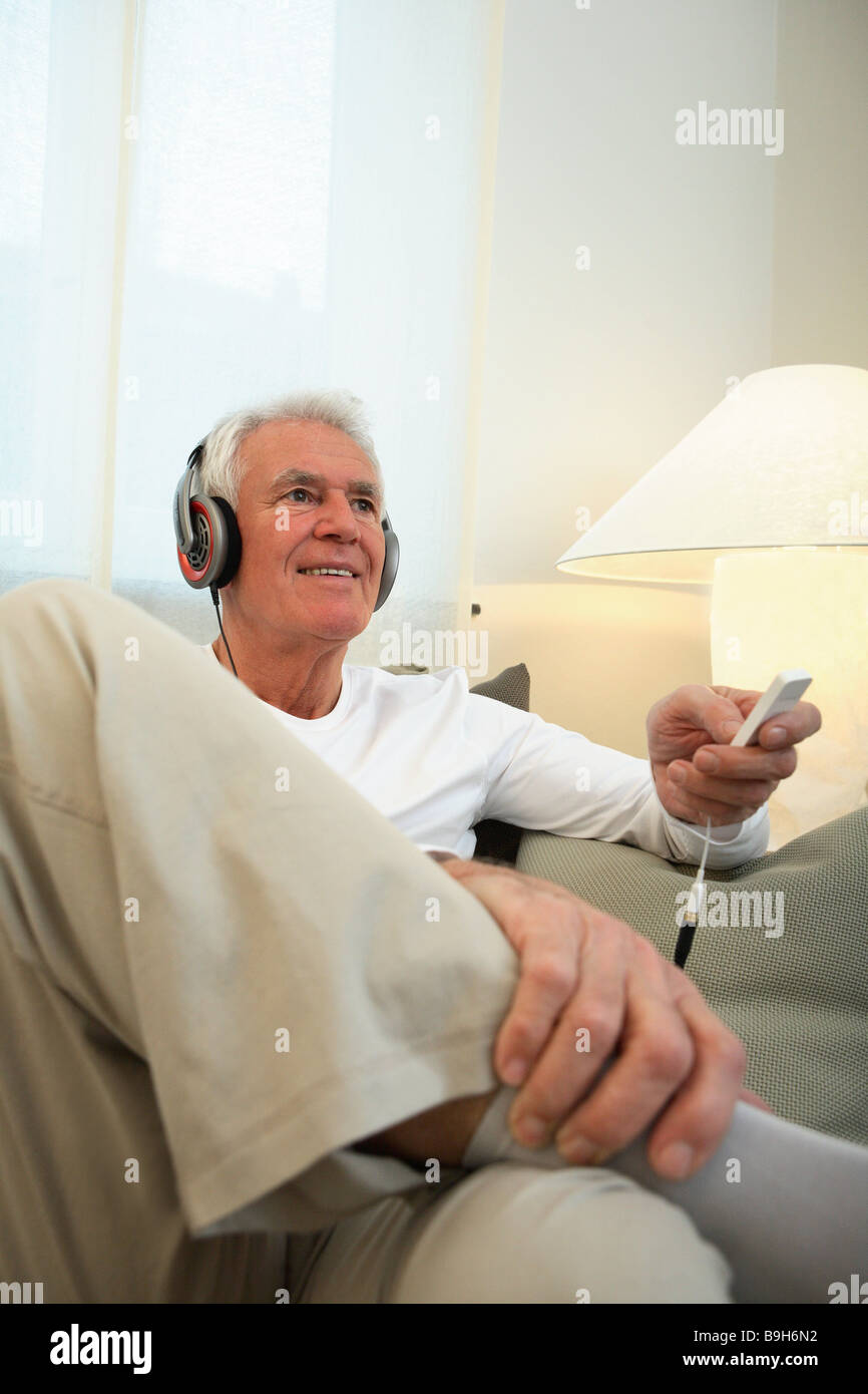 Salon canapé senior casque série assis relaxation personnes aînés retraités l'homme aux cheveux blancs la musique de relaxation-entend Banque D'Images