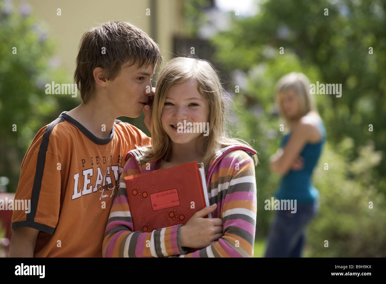 Les élèves garçon fille oreille secret extérieur boutique confiant portrait 13 ans à l'extérieur première whispering aime amis de joie Banque D'Images