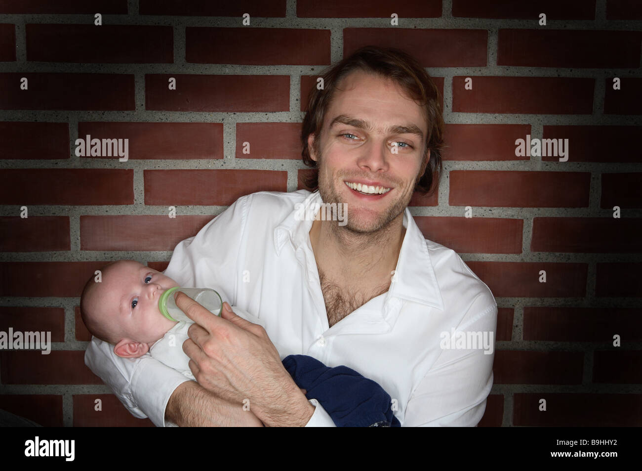 Jeune homme souriant bébé rss personnes portrait flacon de 20 à 30 ans 30 à 40 ans blond foncé barbe de trois jours seul parent gaiement Banque D'Images