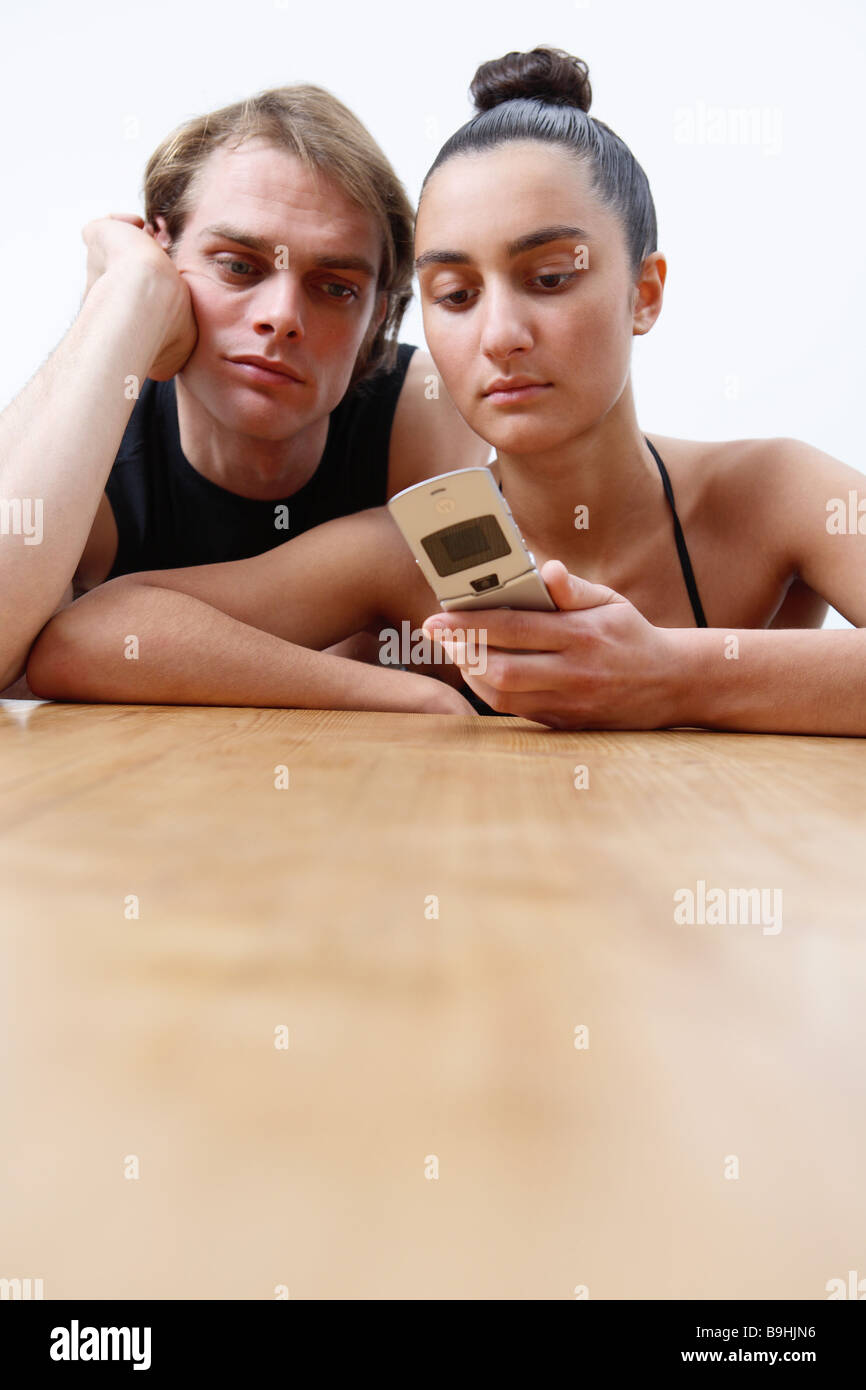 Paire de table jeunes cell phone message vues ennuyer les gens portrait de 20 à 30 ans 30 à 40 ans deux assis côte à côte ensemble Banque D'Images