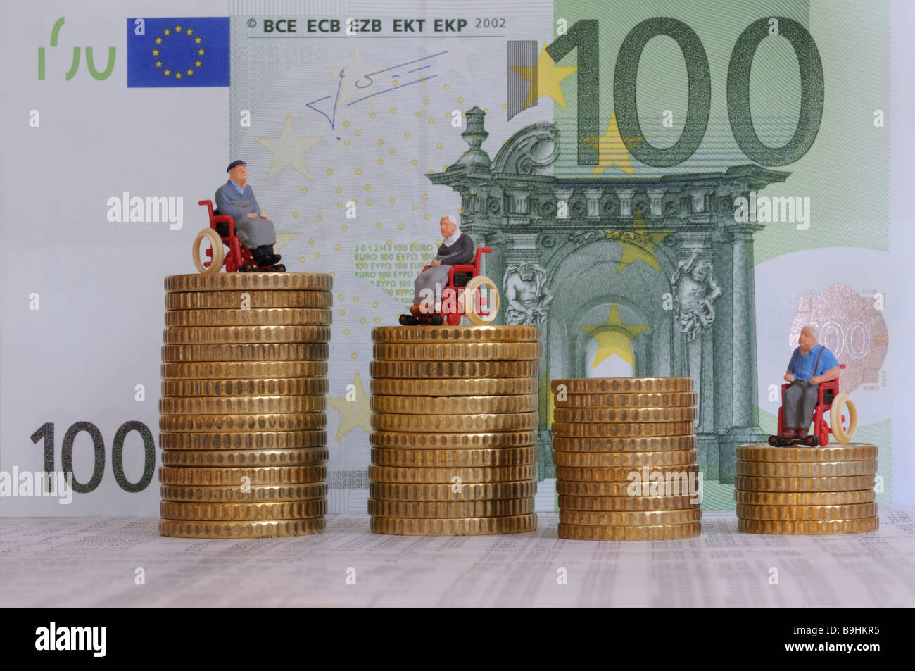 Chiffres utilisateurs de fauteuil roulant sur des piles de pièces de monnaie, en face d'un projet de loi 100 eur, image symbolique d'allocation pour soins Banque D'Images