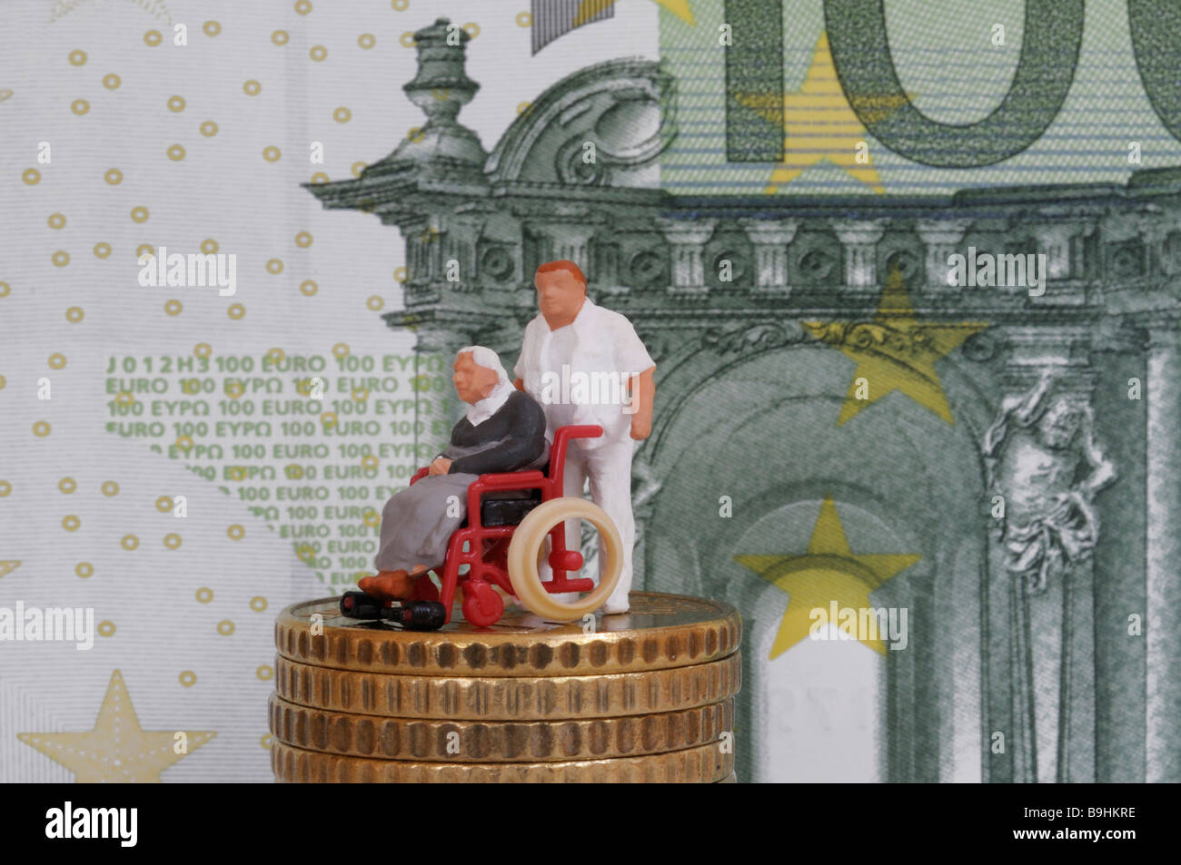 Infirmier en poussant une vieille personne en fauteuil roulant, figure sur une pile de pièces en face d'un projet de loi, 100 EUR pour une photo symbolique Banque D'Images