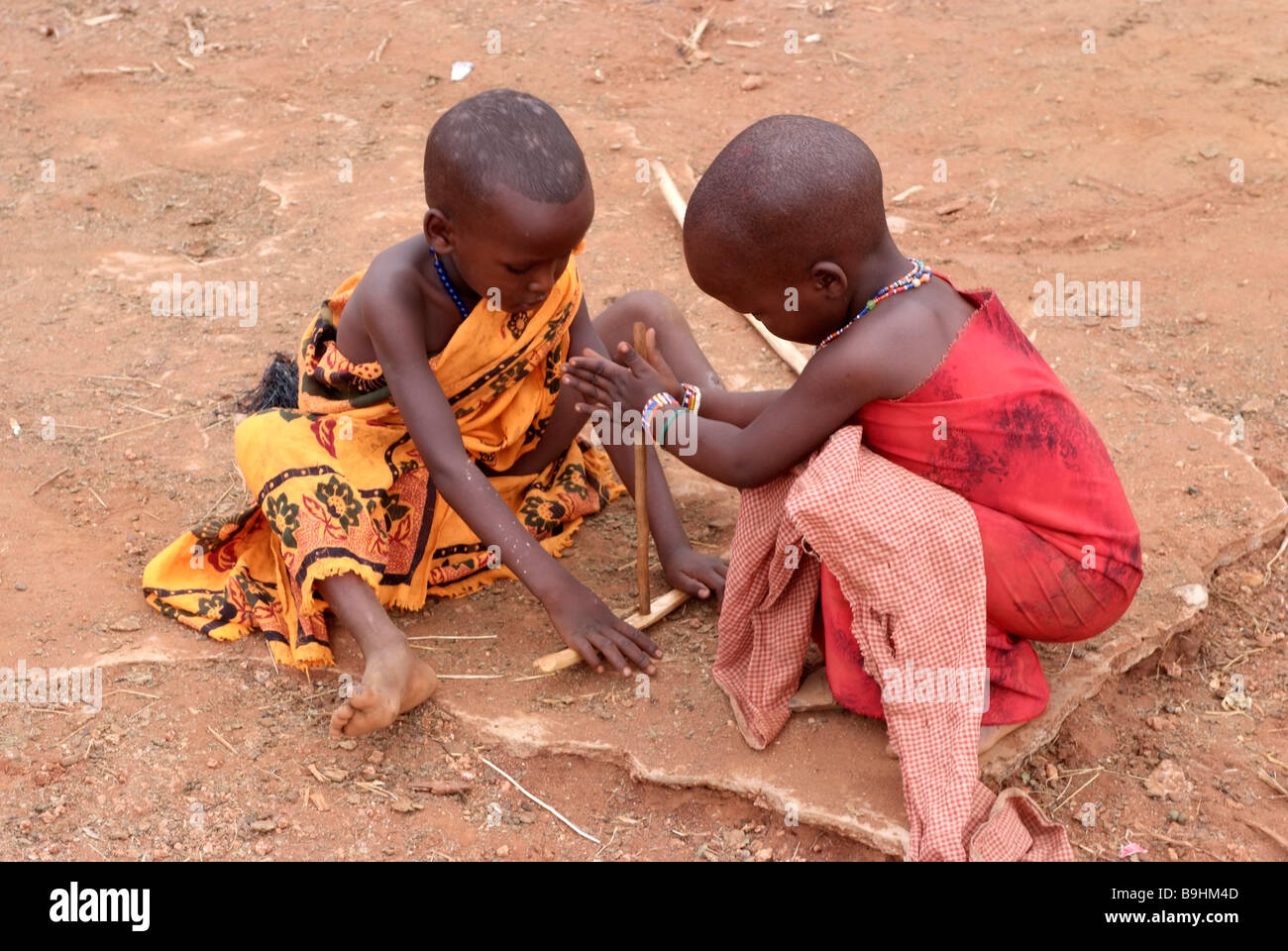 Enfants Massai feignent d'allumer un feu, le Kenya, l'Afrique Banque D'Images