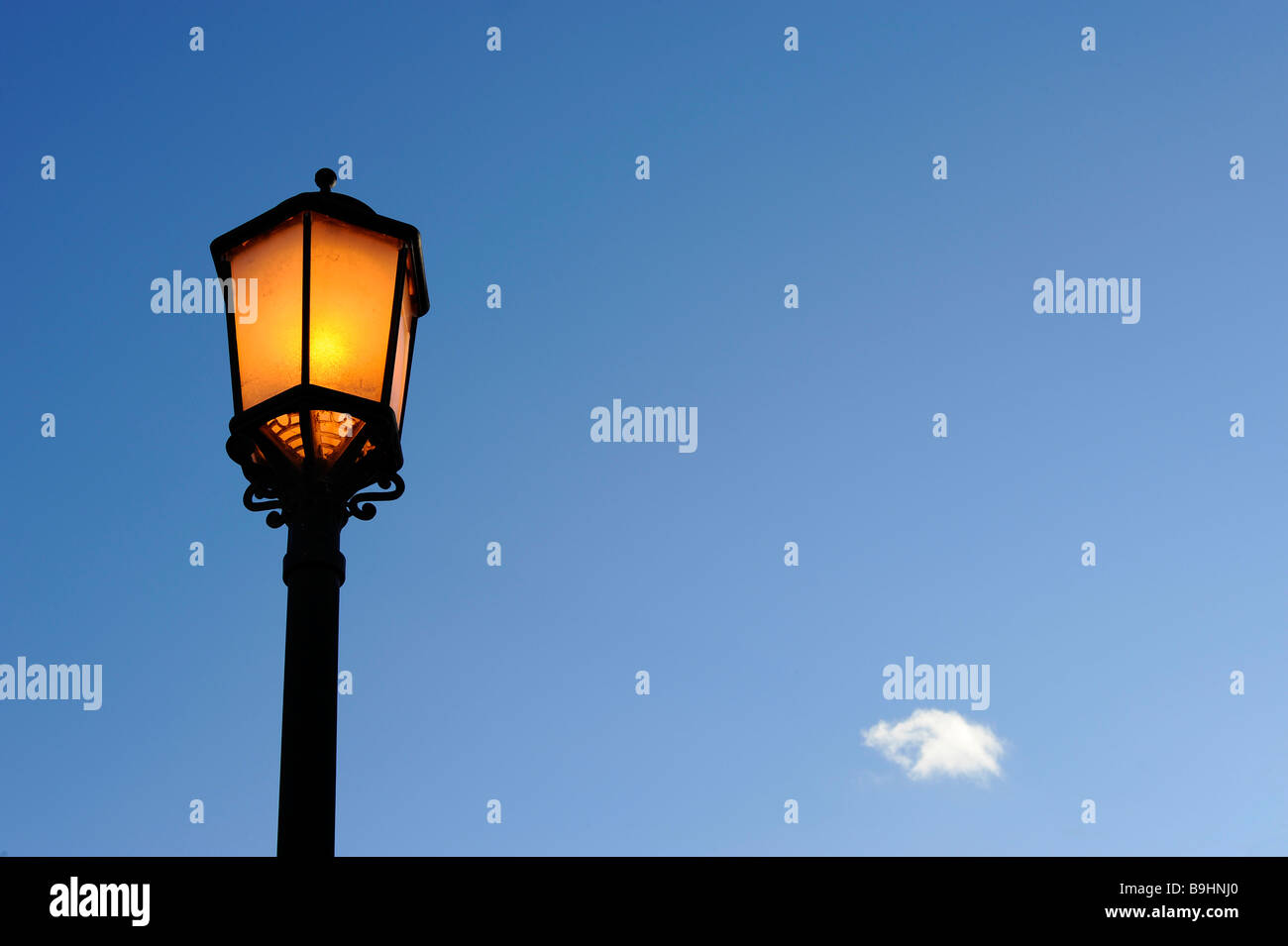 Jaune lanterne de rue contre un ciel bleu avec un seul nuage Banque D'Images