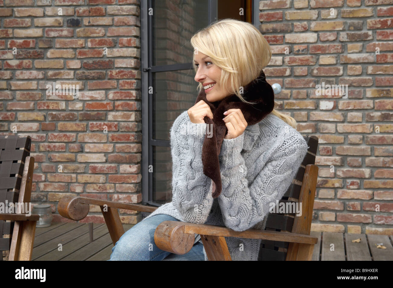 Portrait d'une belle blonde femme assise à l'extérieur et portant un foulard fausse fourrure Banque D'Images