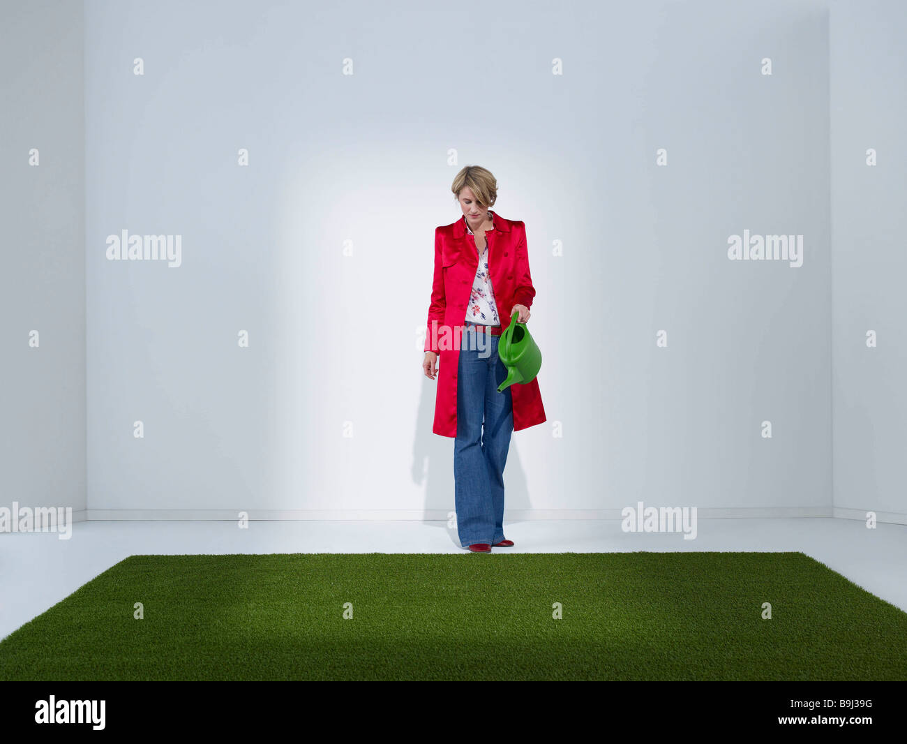 Femme en vert gazon arrosage bureau Banque D'Images