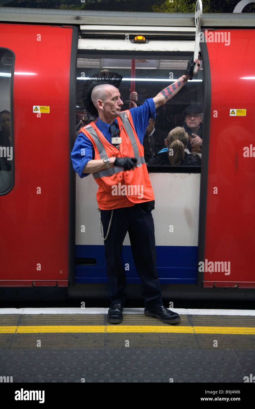 Un garde sur une plate-forme de la station de métro à Londres avec un coupe mohican Banque D'Images