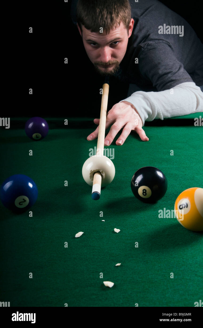 Un pool shark touchera un queue à travers une boule de choc Banque D'Images