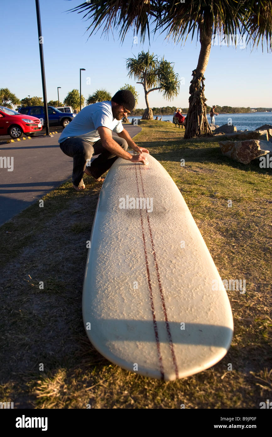 Les cires d'un surfer son conseil avant d'aller surfer à Noosa dans le Queensland, Australie Banque D'Images