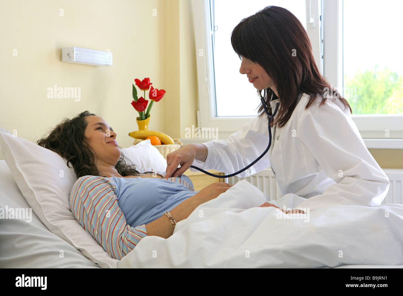 L'examen du médecin de l'hôpital femme enceinte de 20 à 30 ans 30 à 40 ans Profession Médecin lit soins livraison de la pression artérielle Banque D'Images