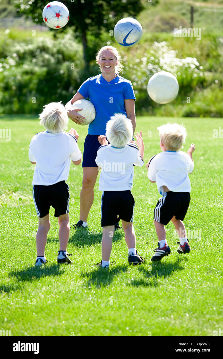 Une mère son coaching trois petits garçons au cours d'entraînement de soccer. Banque D'Images
