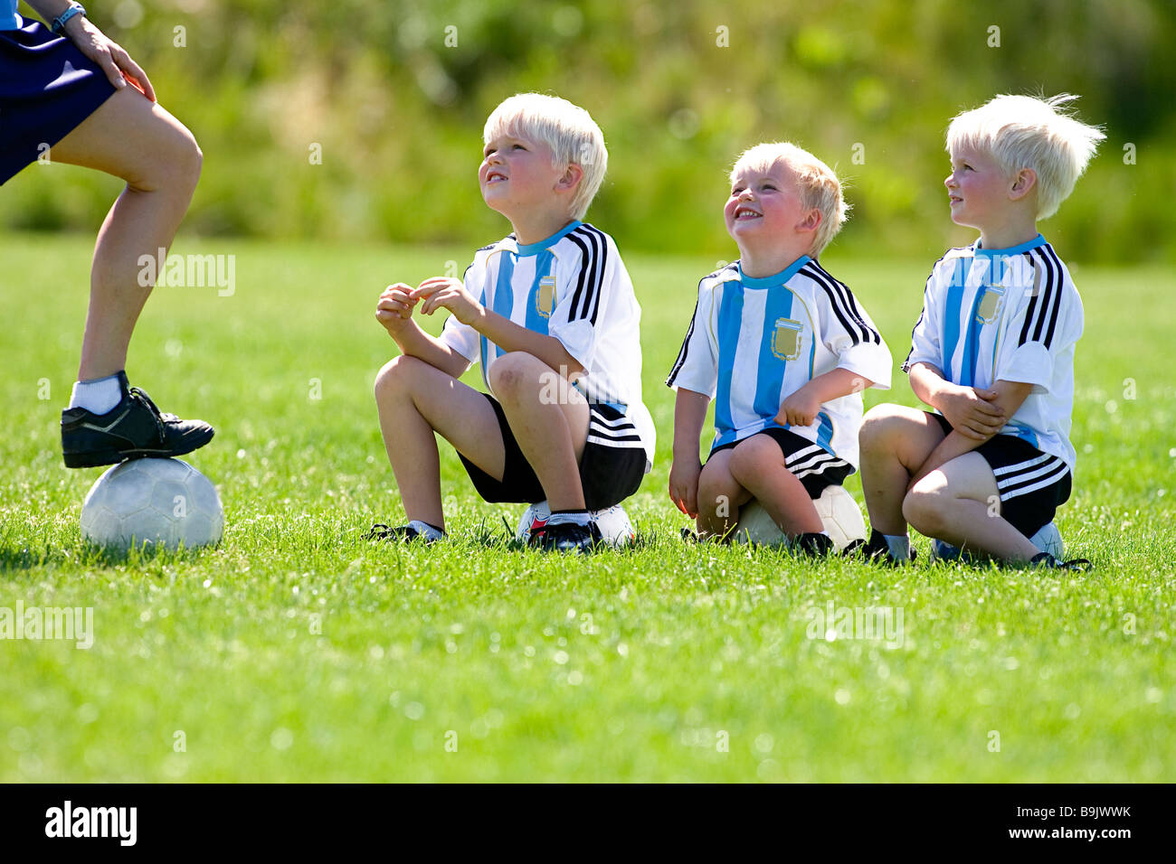 Une mère son coaching trois petits garçons au cours d'entraînement de soccer. Banque D'Images