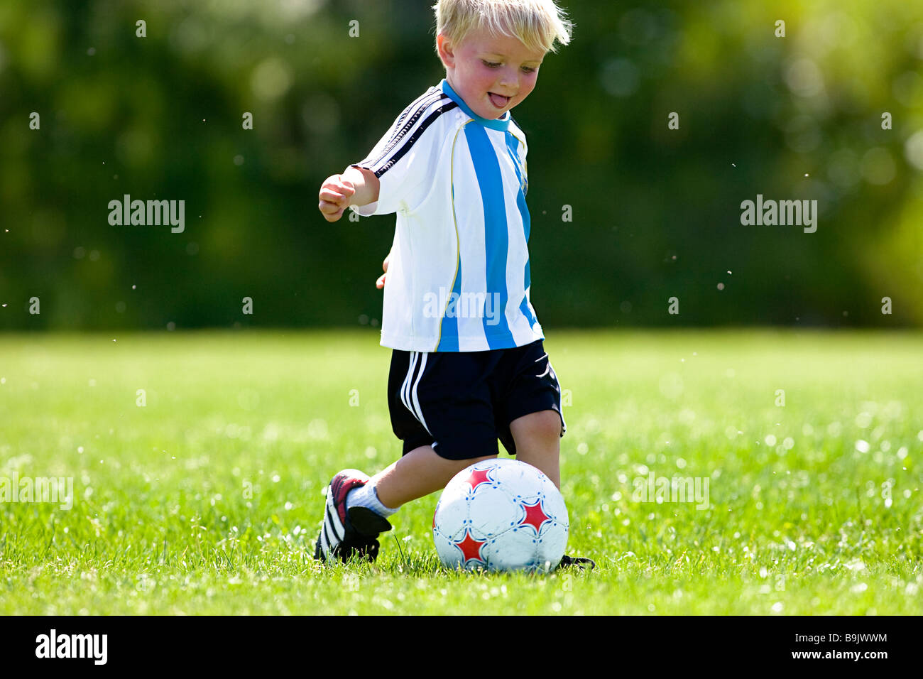 Un jeune garçon souriant et jouer au soccer. Banque D'Images