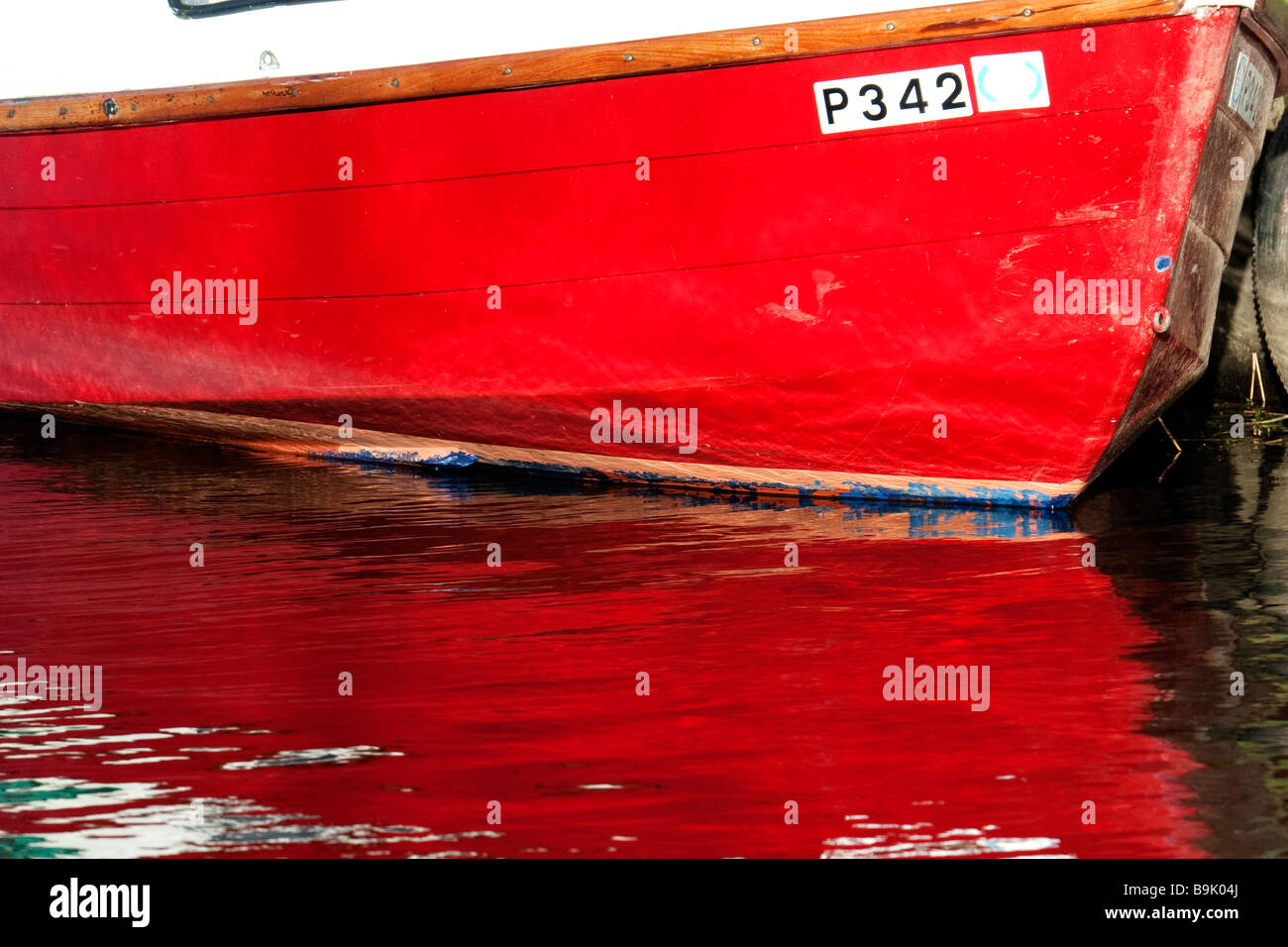 Coque de bateau peint rouge détail reflétant dans la rivière Banque D'Images