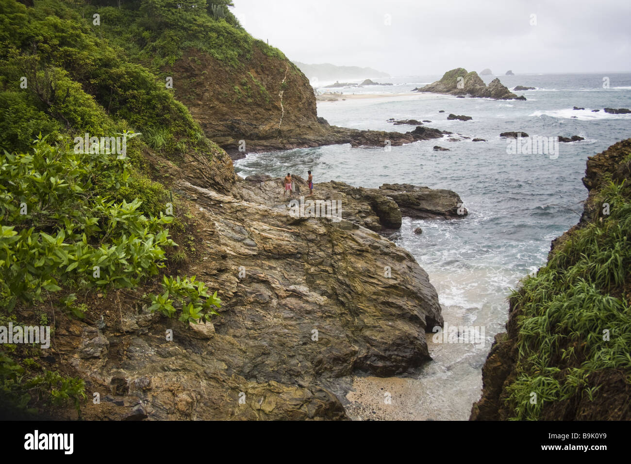 Les pêcheurs de se tenir sur les rives rocheuses de l'océan Pacifique près du village de Mazunte, Oaxaca, Mexique. Banque D'Images
