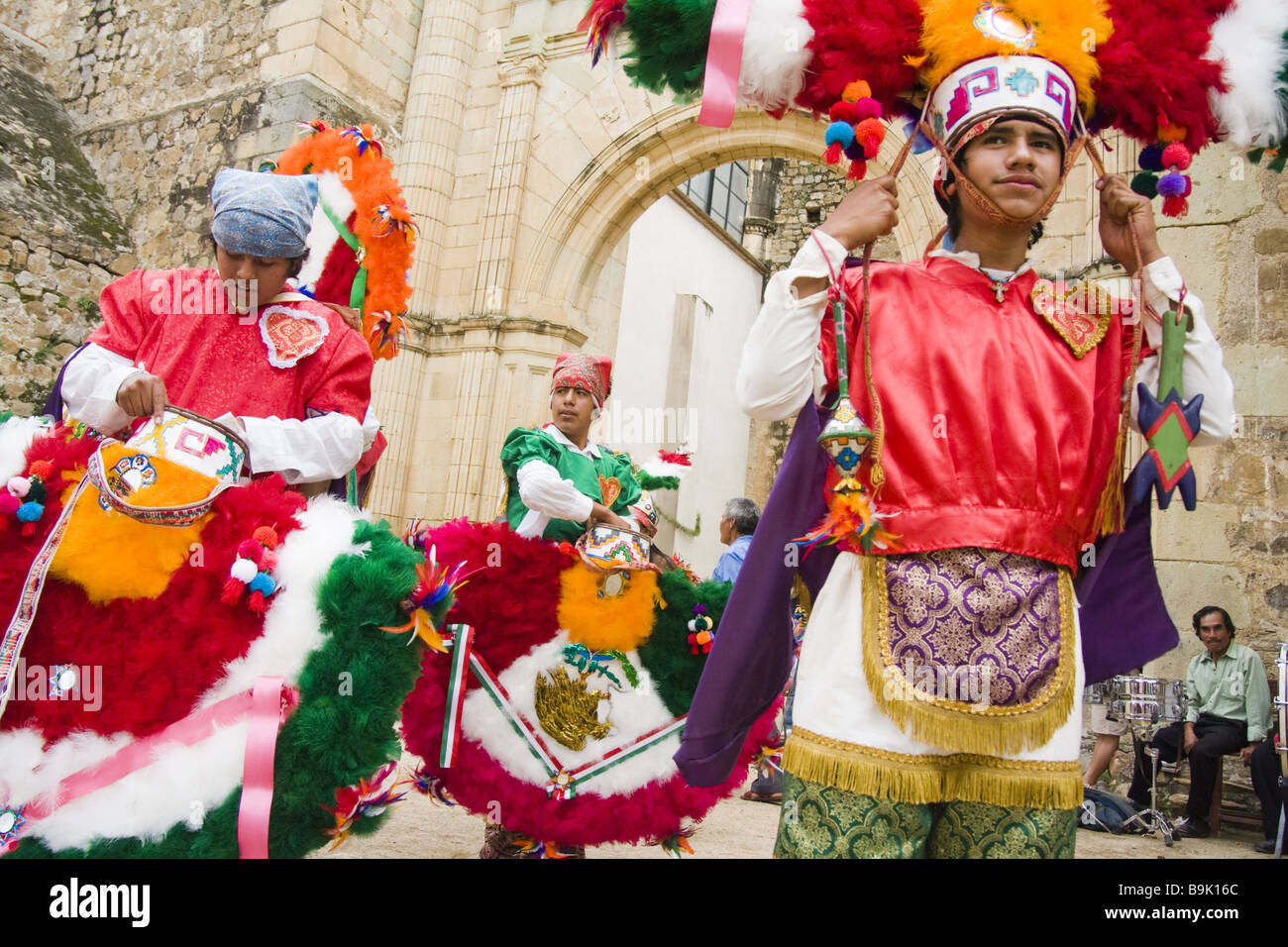 Danseurs de la Danza de la Pluma ajuster leurs coiffes en face du monastère et église de Cuilapan, Oaxaca, Mexique. Banque D'Images