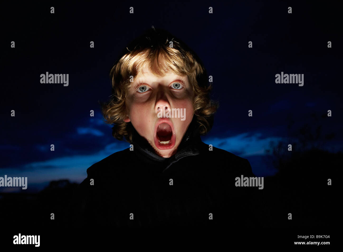 Boy making faces avec torche Banque D'Images