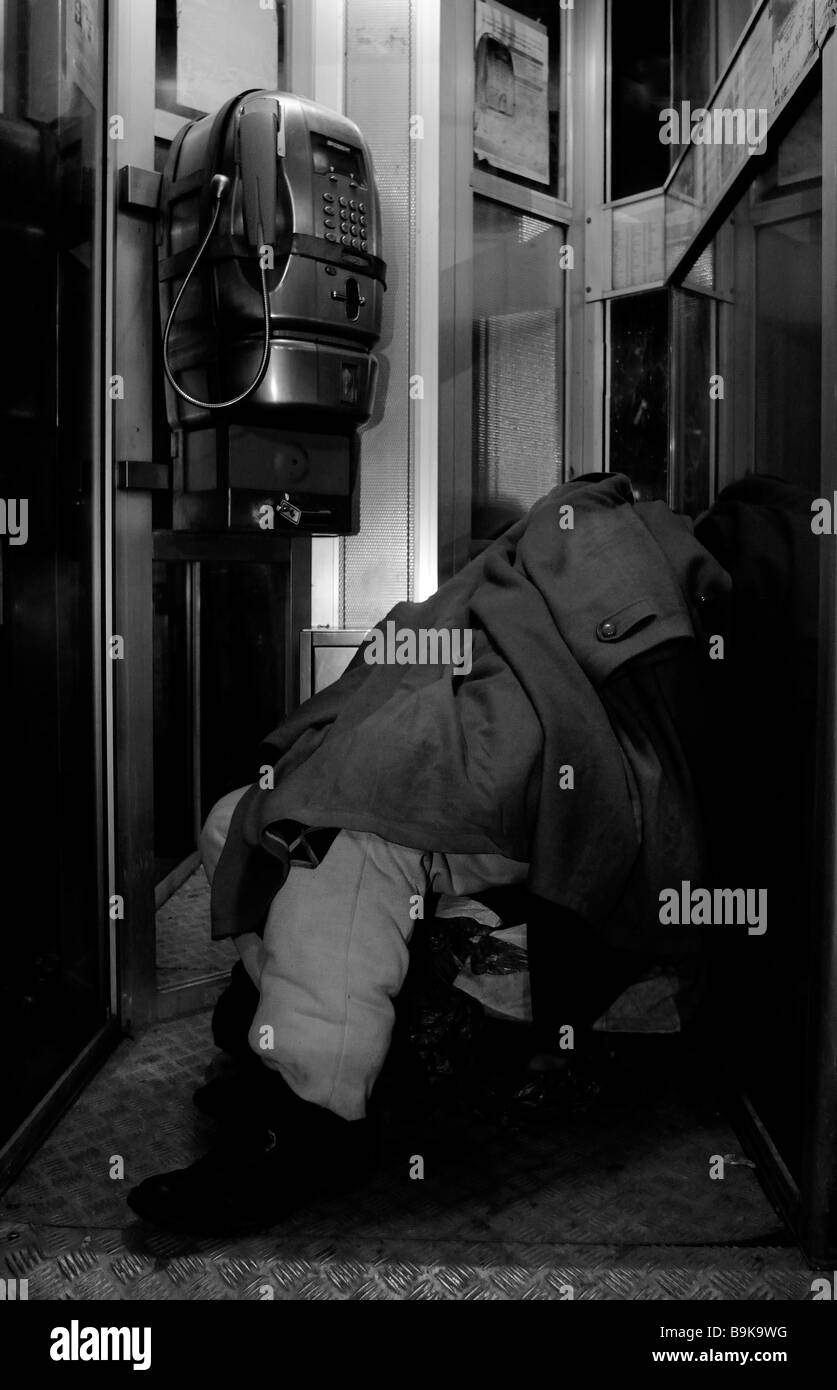 Sans-abri dormant dans une cabine téléphonique Banque D'Images