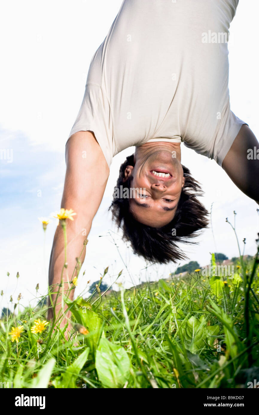 Young man doing handstand on grass Banque D'Images