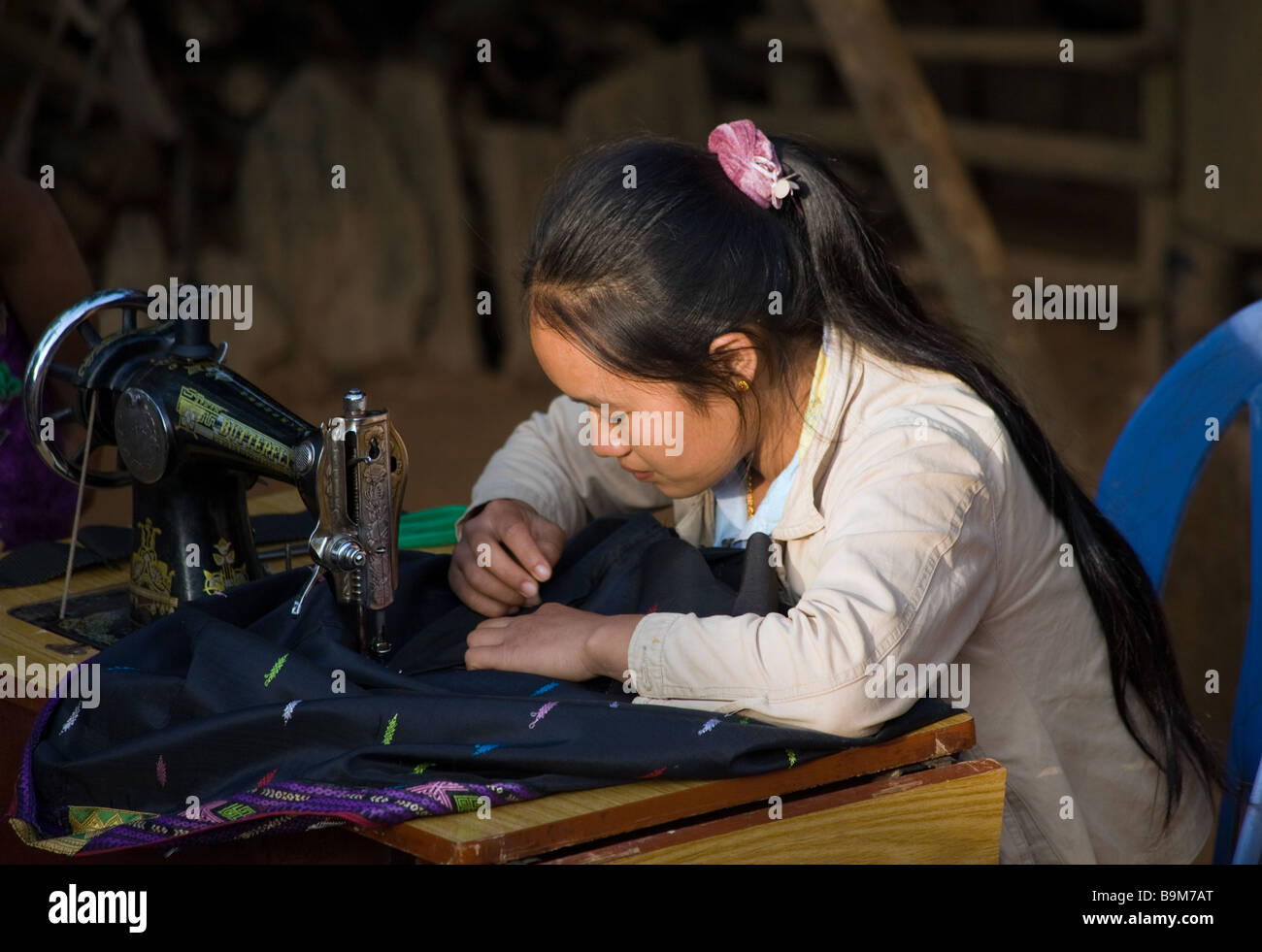 Dans un petit village entre Luang Prabang et Phonsavan une jeune femme coud une robe nouvel an Hmong traditionnelle sur une machine à coudre Banque D'Images
