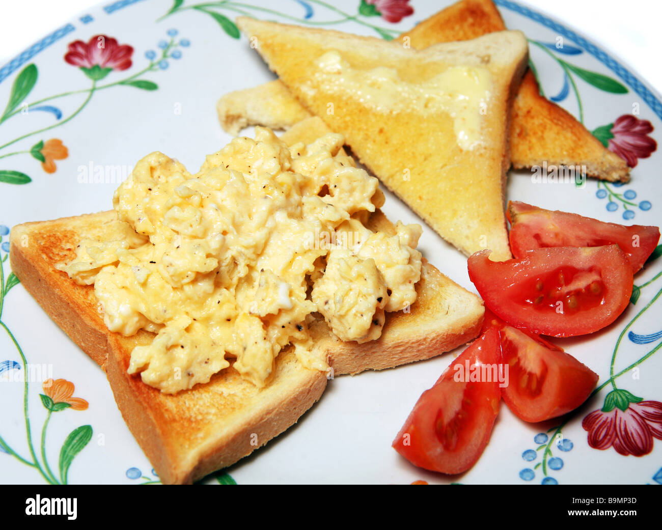 Des œufs brouillés sur toast avec une tomate fraîche. Banque D'Images