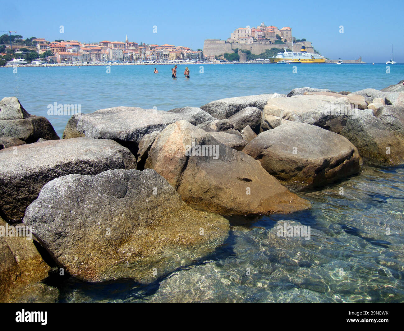 Le front de mer, mer et rochers avec la citadelle de Calvi à l'arrière-plan Calvi, Corse, France. Banque D'Images