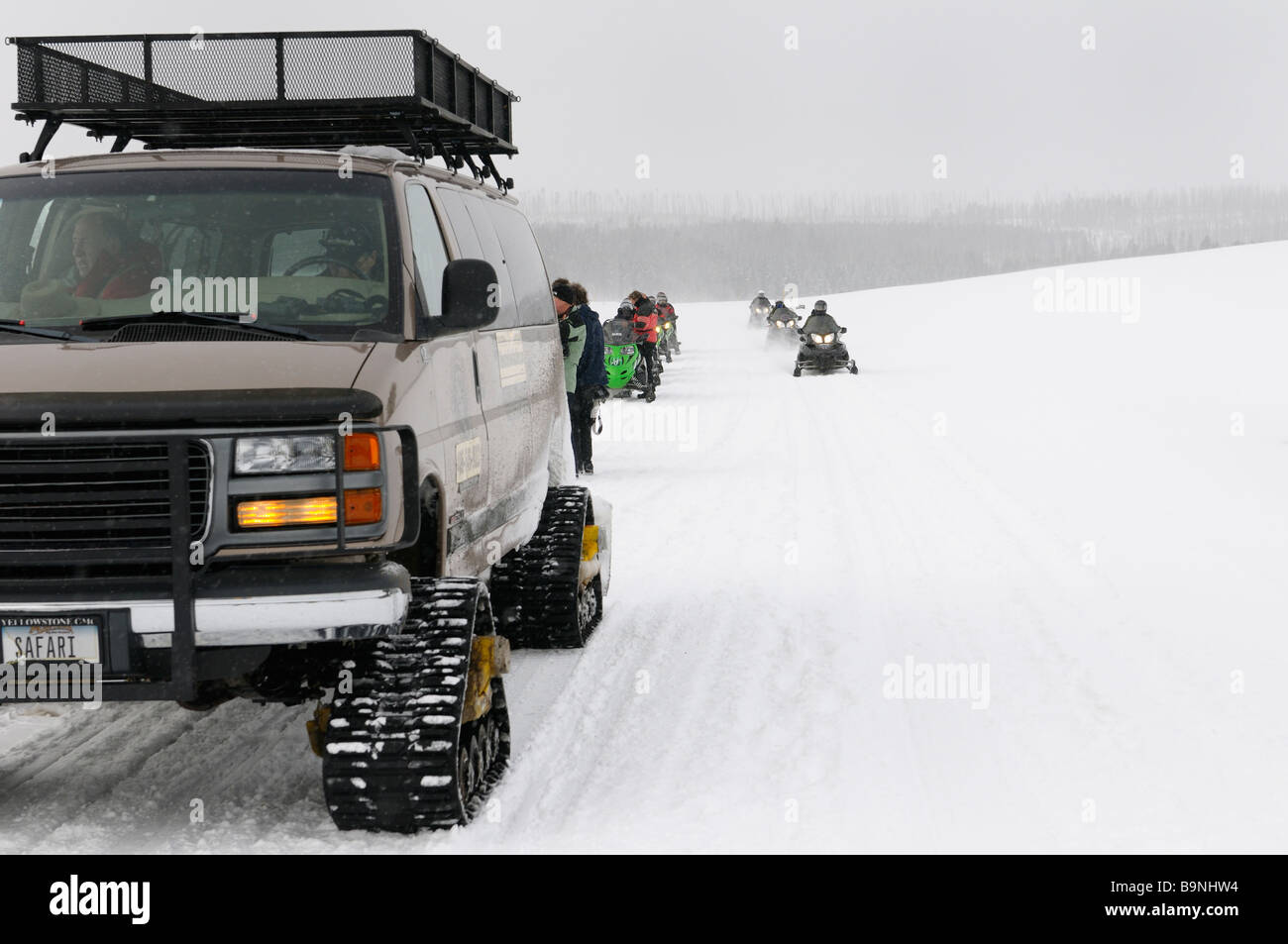 Snowmobiler et groupe snowcoach arrêté pour photos sur Norris Canyon Road dans le Parc National de Yellowstone en hiver Banque D'Images