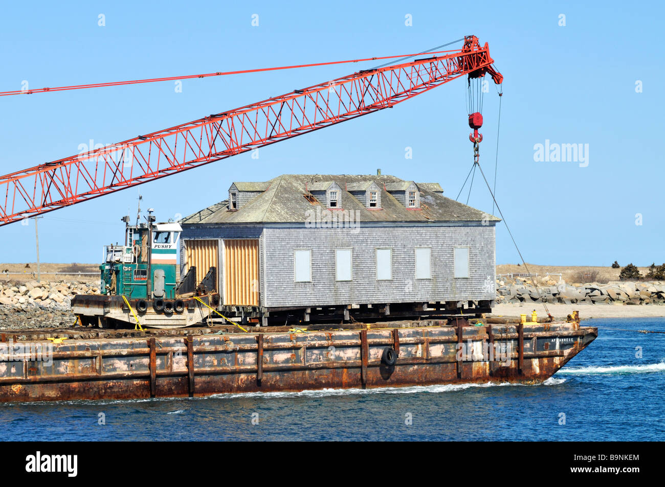 Ancien hangar à bateaux de la Garde côtière canadienne d'être transportés par barge à travers 'Cape Cod Canal' Banque D'Images