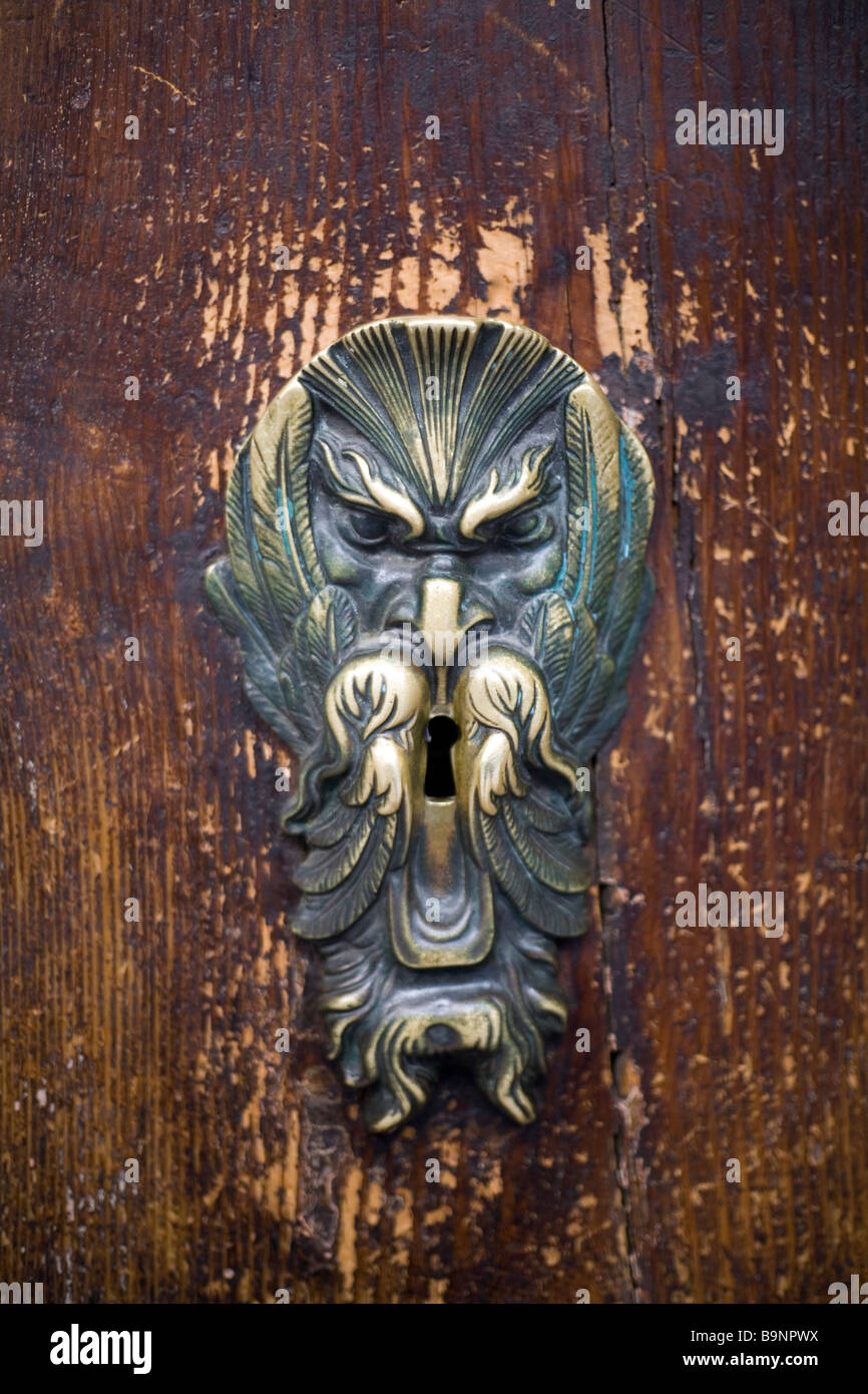 Un doorknocker dans la forme d'un visage barbu sur une porte rouge à Bologne Italie Banque D'Images