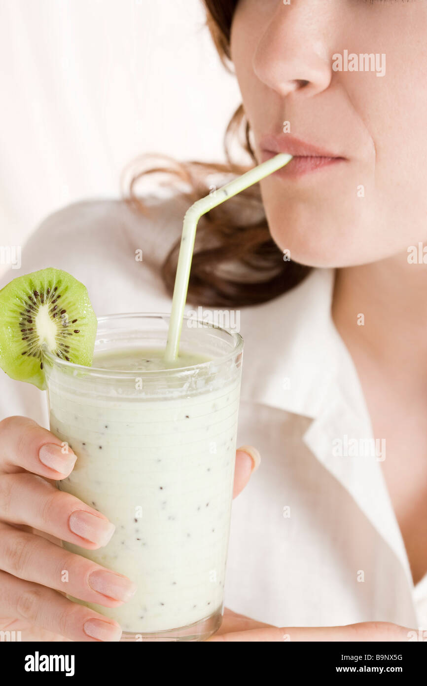 Close-up of woman drinking milk-shake kiwi Banque D'Images