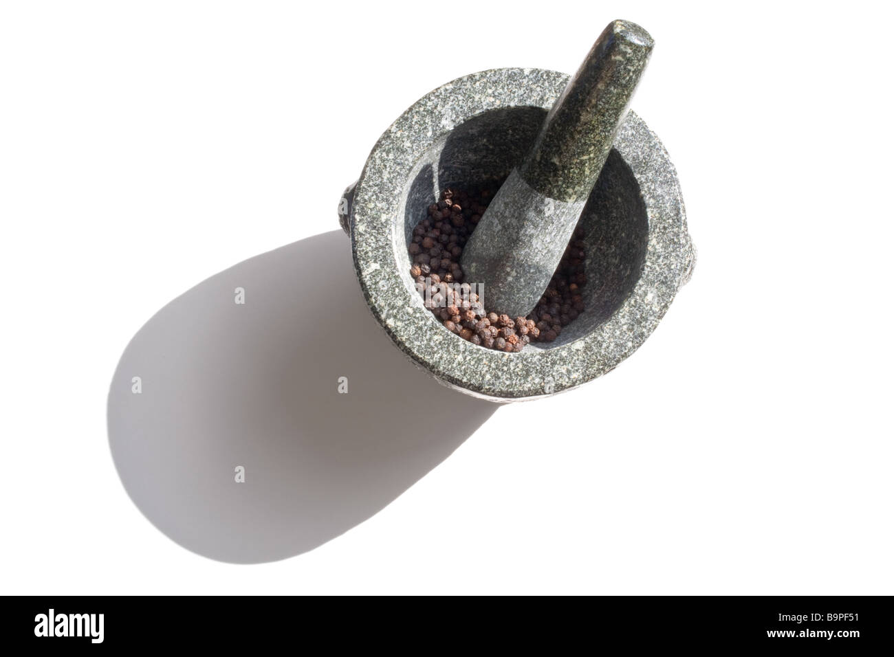 Mortier et pilon en granit avec poivre noir sur un fond blanc. Banque D'Images