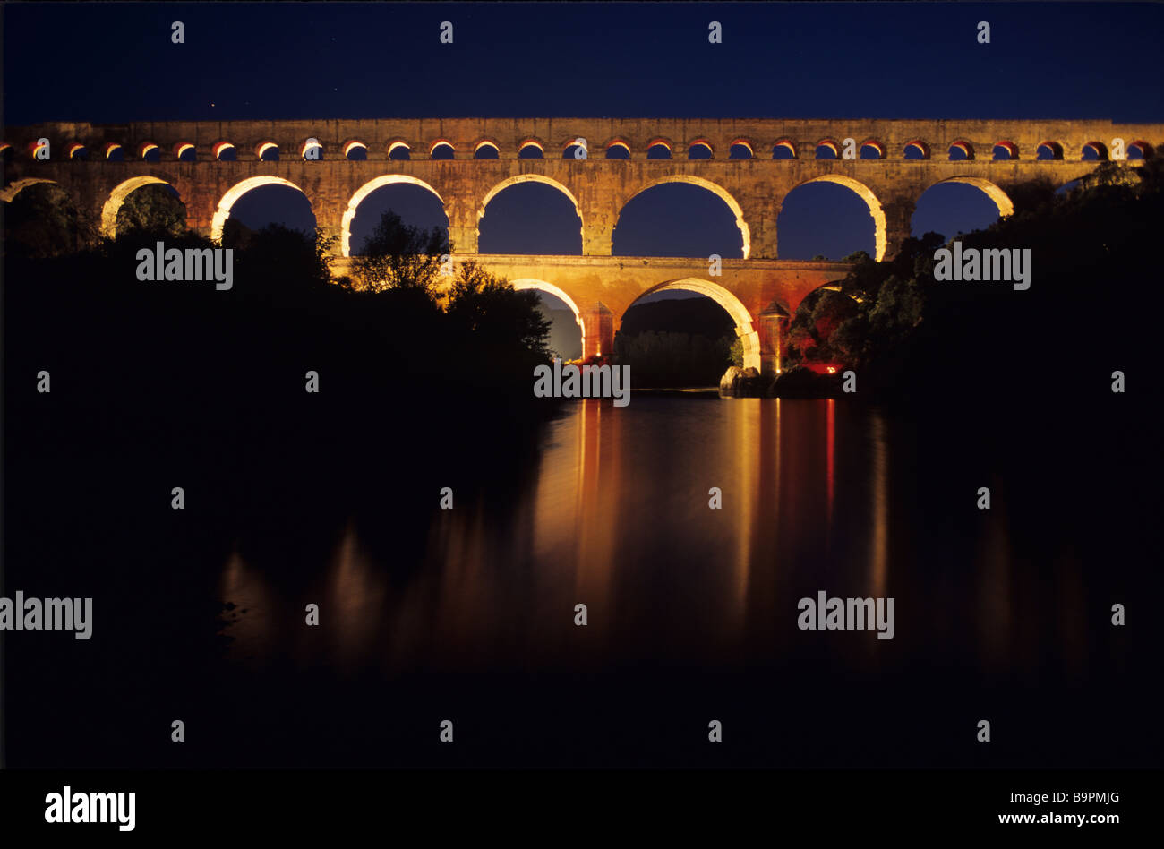 Vue de nuit de l'Aqueduc Romain, le Pont du Gard (c1stBC) éclairé la nuit et reflétée dans le Gard, près de Nimes, France Banque D'Images