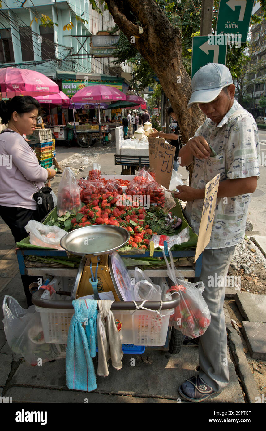 Une femme thaïlandaise achète des fraises fraîches dans un étalage de rue à Bangkok Thaïlande Banque D'Images