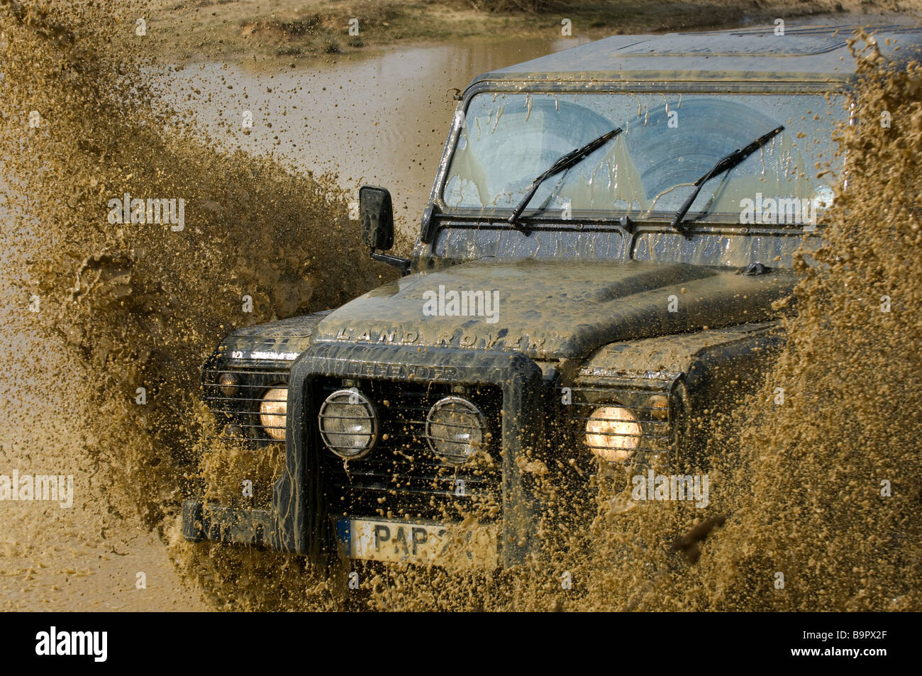 Une Land Rover Defender 90 touches au moyen d'une rivière. Banque D'Images