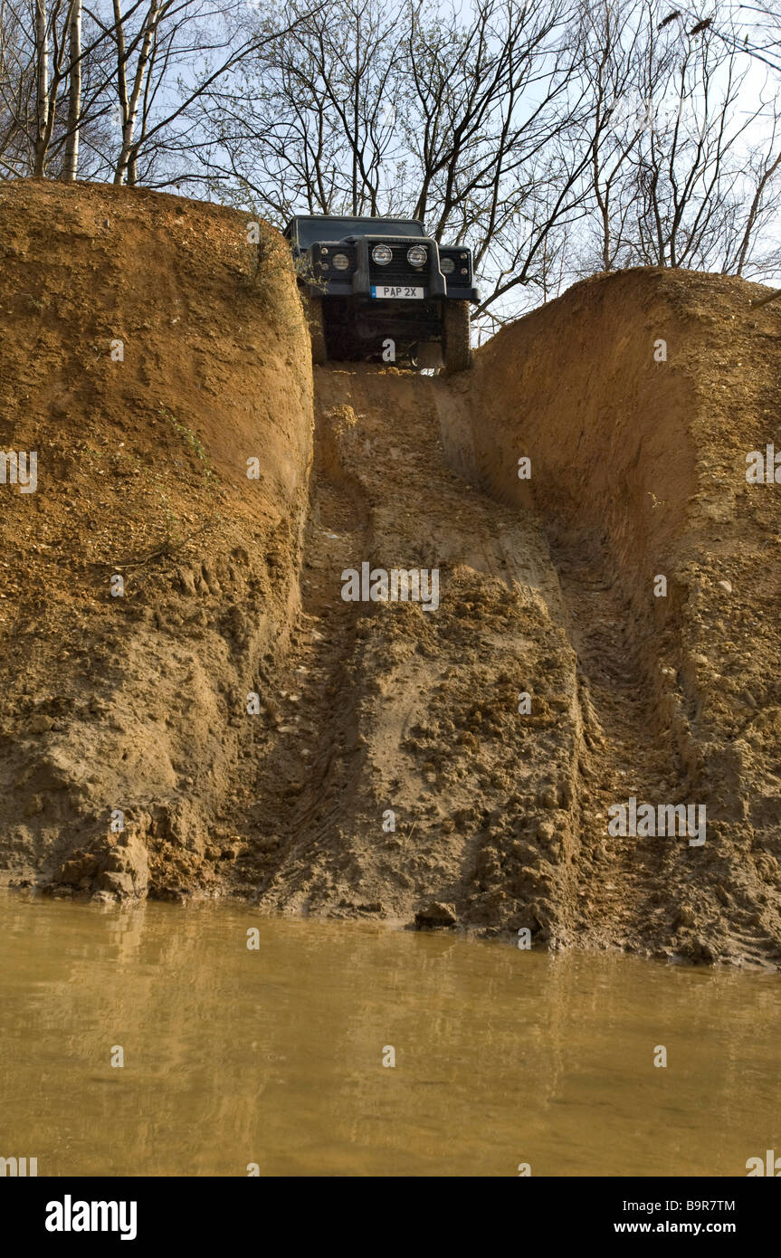 Une Land Rover Defender 90 sur le point de descendre une pente raide dans une rivière sur une piste de conduite hors route dans le Sussex au Royaume-Uni. Banque D'Images