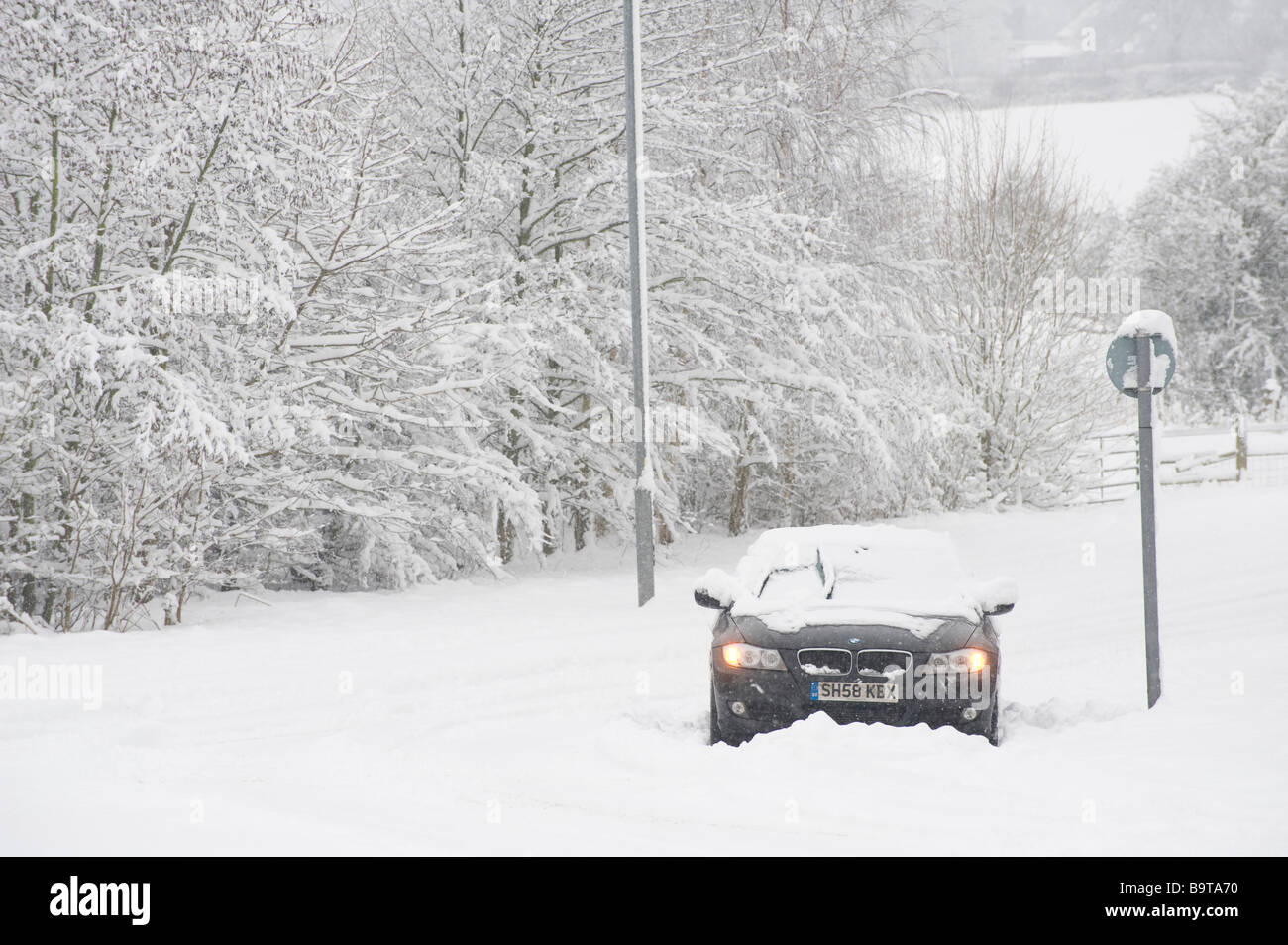 Voiture BMW abandonnés dans la neige épaisse avec des feux de détresse sur le côté de la route sur une journée l'hiver en Angleterre Banque D'Images