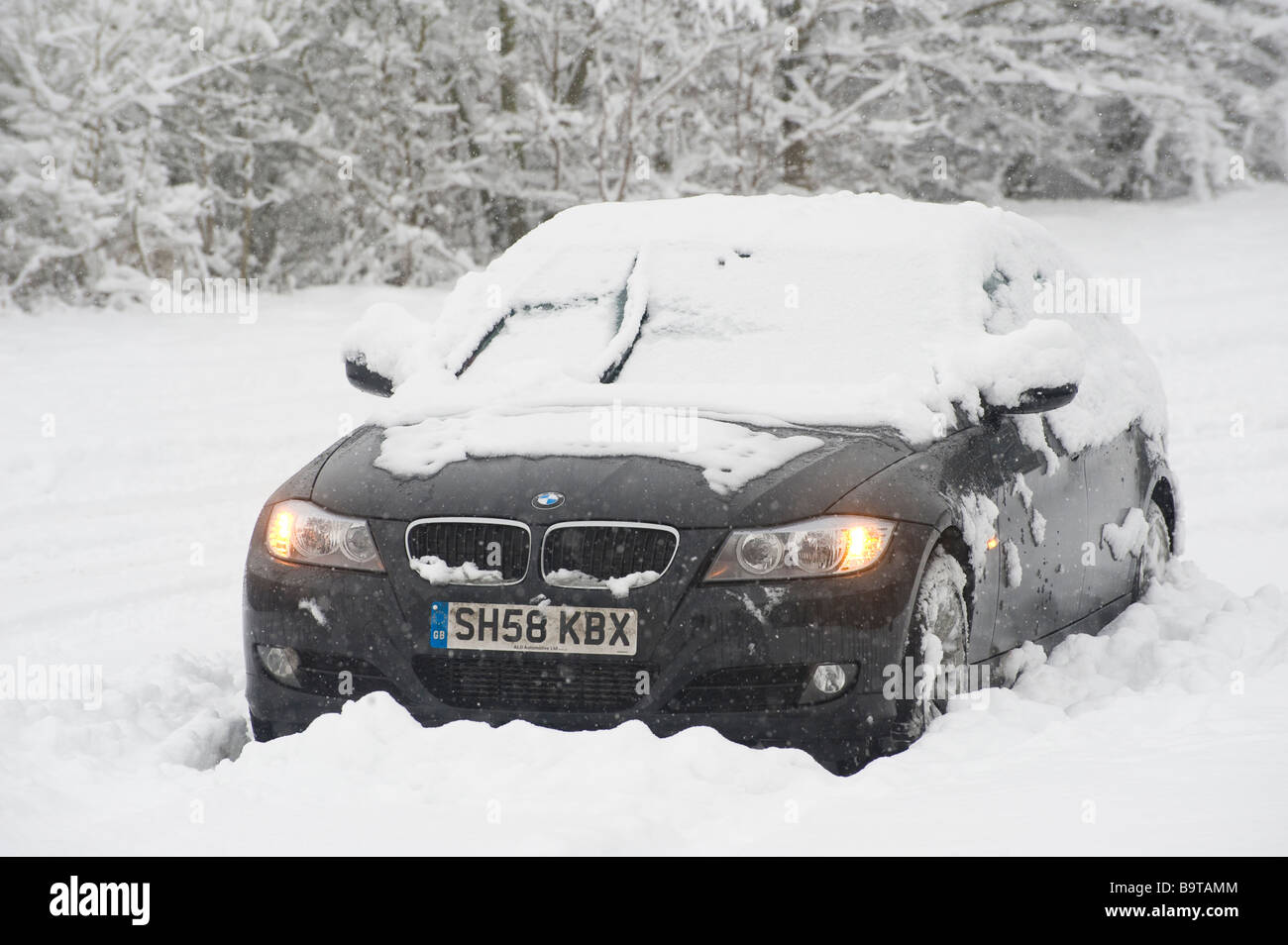 Voiture BMW abandonnés dans la neige épaisse avec les feux de falshing sur le côté de la route sur une journée l'hiver en Angleterre Banque D'Images