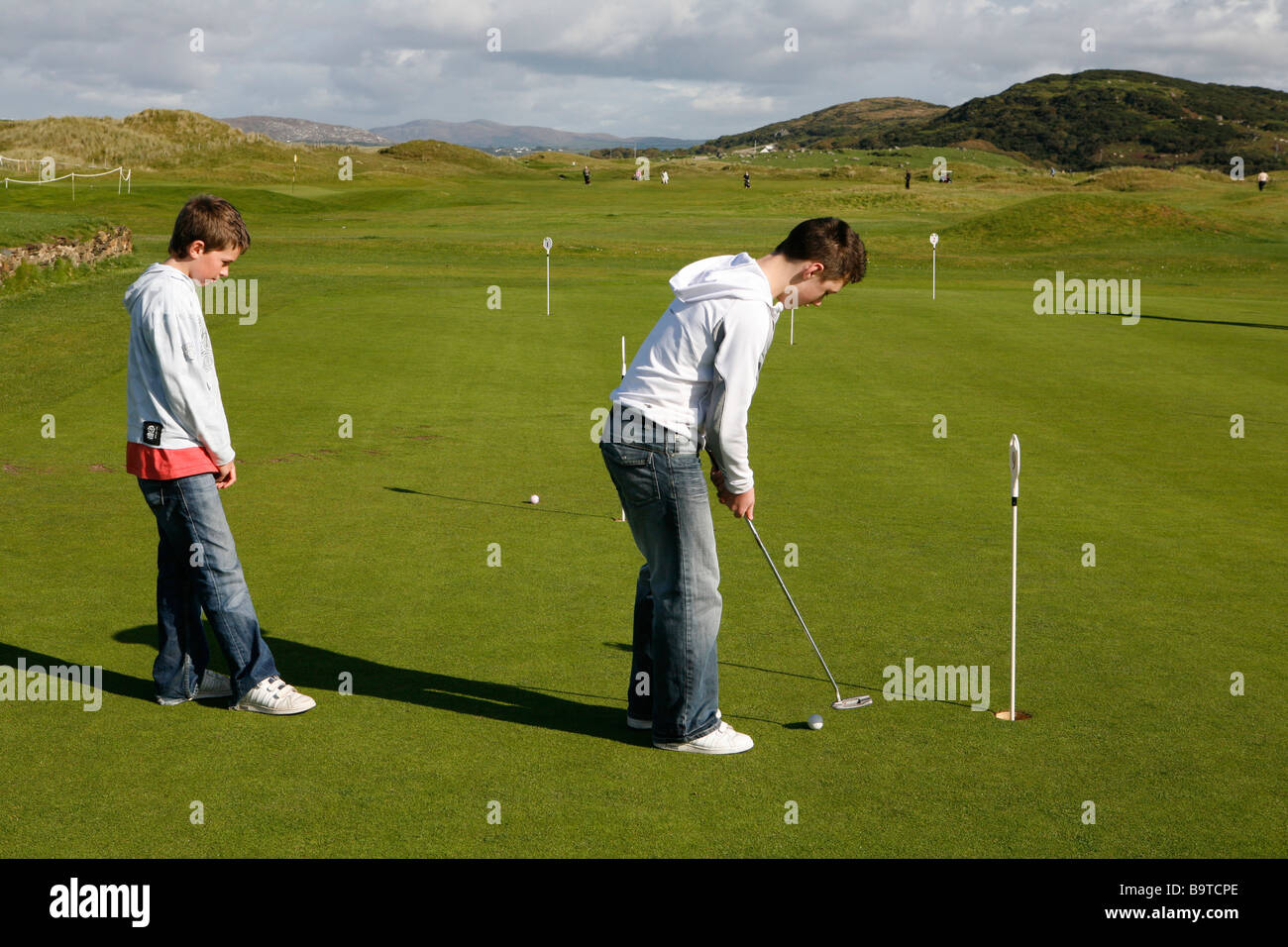 Deux garçons pratiquer le golf, sur un parcours de golf sur la côte ouest de Donegal, comté de Donegal, en République d'Irlande. Banque D'Images