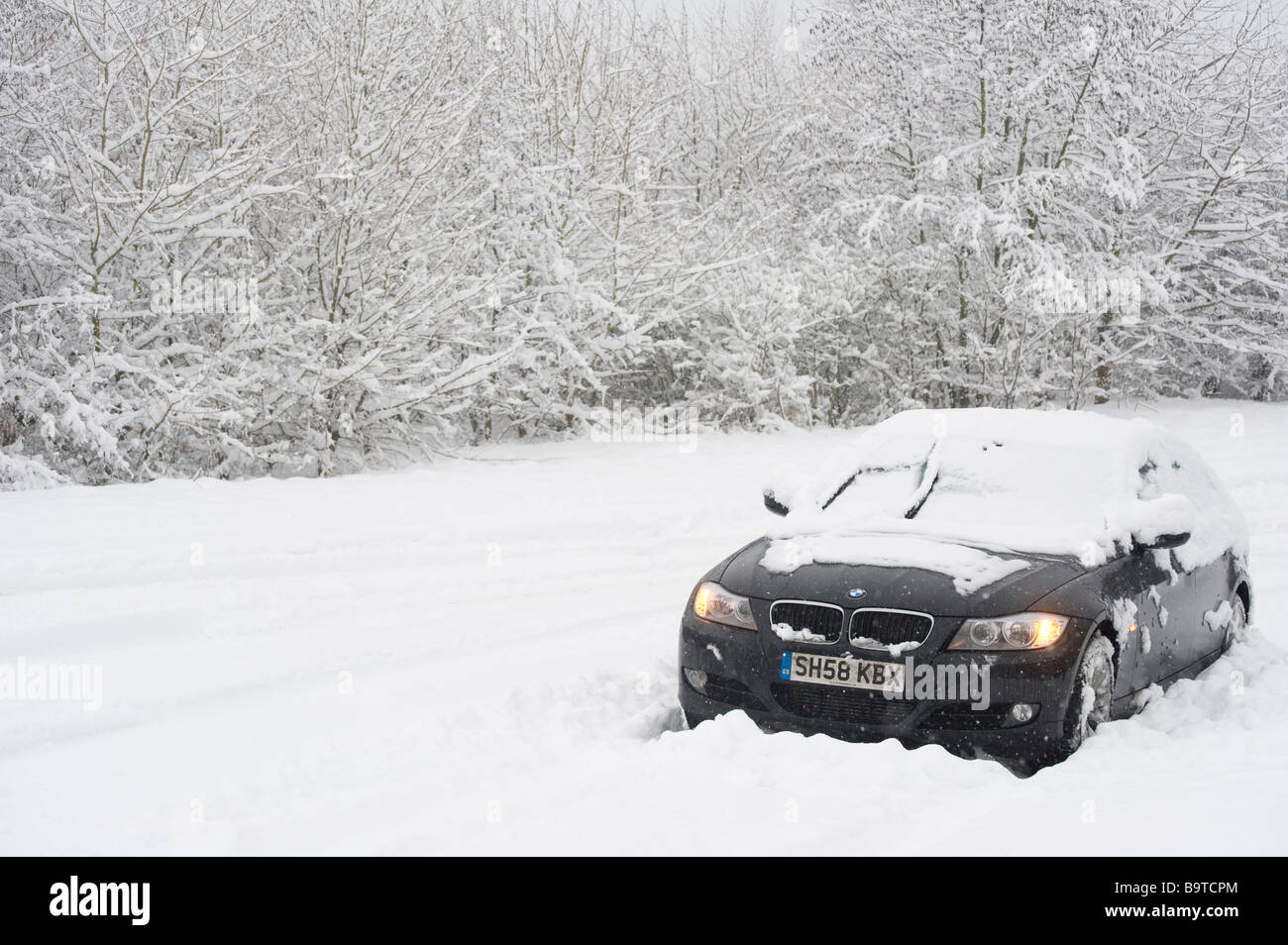 Voiture BMW abandonnés dans la neige épaisse avec des feux de détresse sur le côté de la route sur une journée l'hiver en Angleterre Banque D'Images