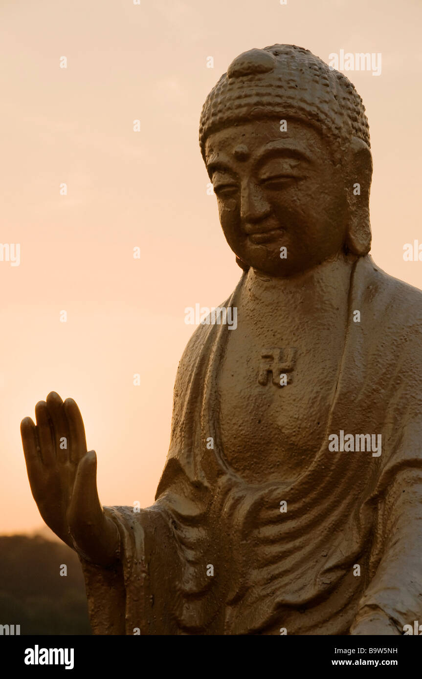 Statue en or de Bouddha avec la main étendue sur le signe de la paix et de ciel rose illuminée par la lumière de soleil de montagne de Bouddha Banque D'Images