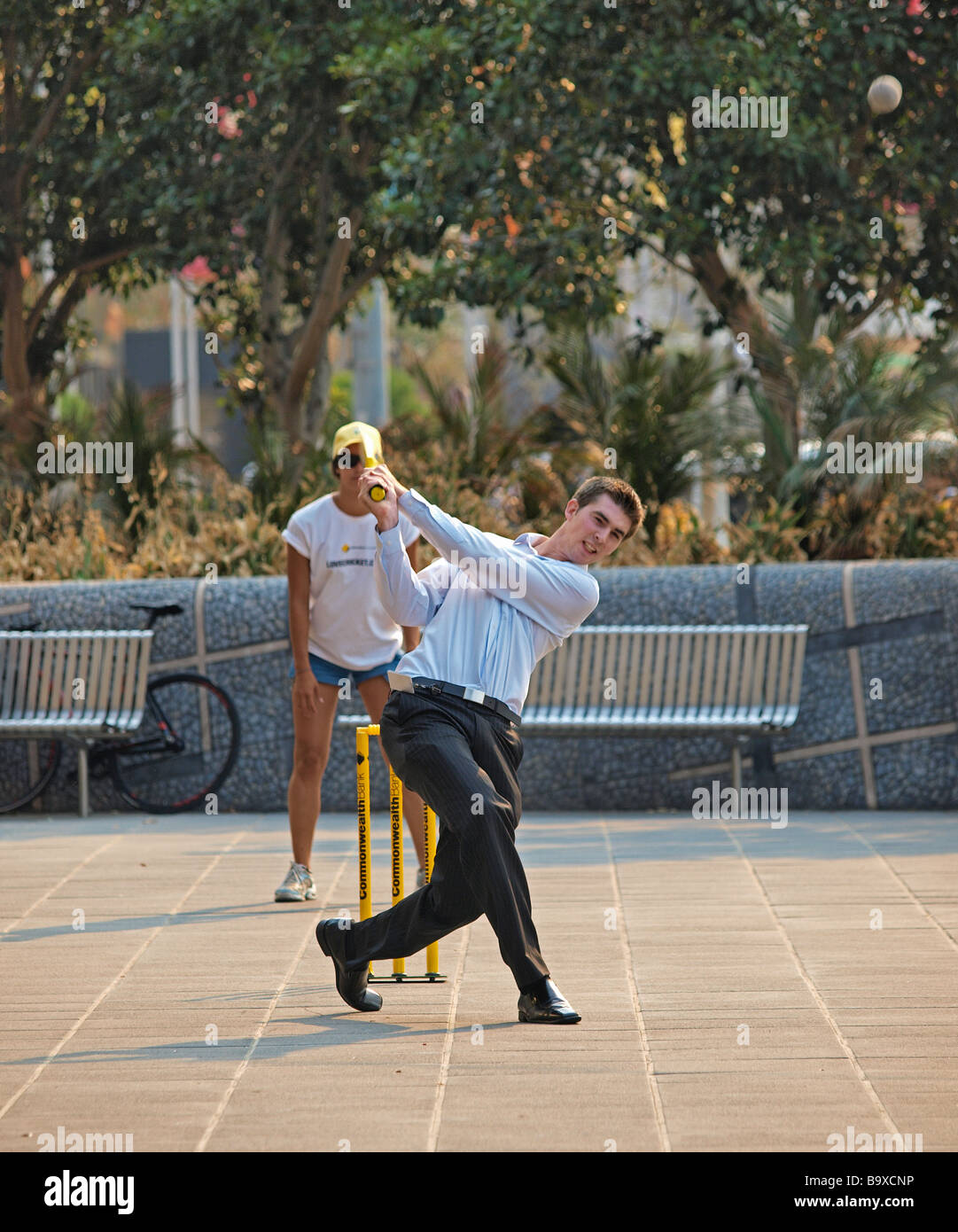 EMPLOYÉ DE BUREAU JOUANT AU CRICKET DE RUE, PUISSANTE FRAPPE DE BALLE, SOUTHBANK MELBOURNE VICTORIA AUSTRALIE Banque D'Images