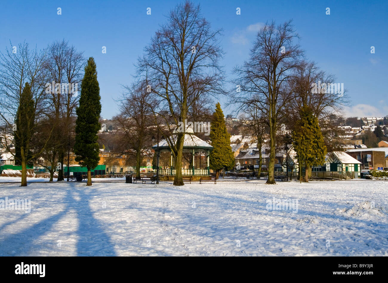 Voir de la neige dans le hall Leys Matlock Derbyshire, Angleterre parc à la recherche à travers les arbres vers le kiosque avec ciel bleu Banque D'Images