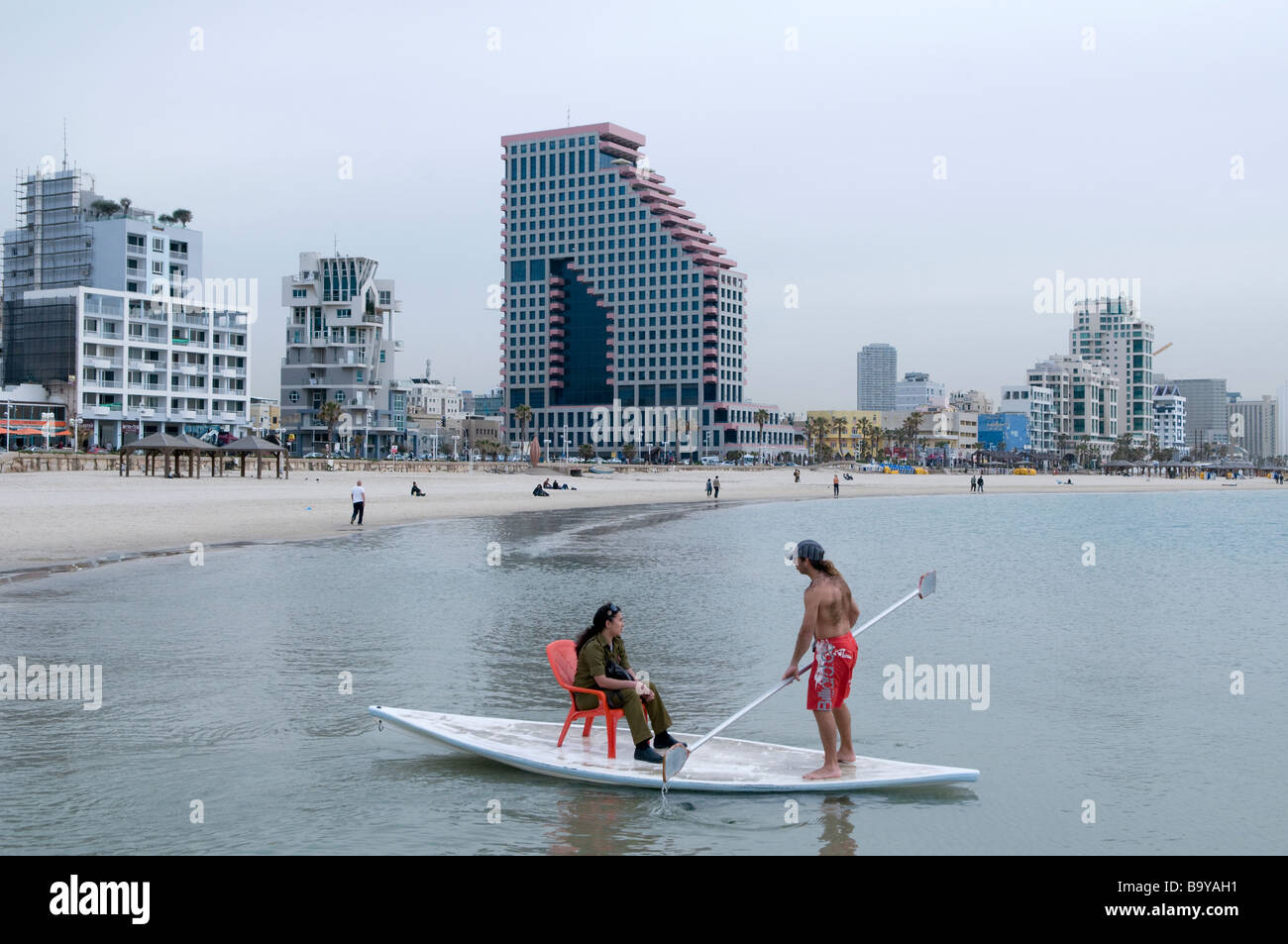 Femme soldat israélien est assis sur ce qu'on appelle un conseil Hasake-voile hybride des Stand-up Paddle en famille le littoral méditerranéen d'Israël Tel Aviv Banque D'Images