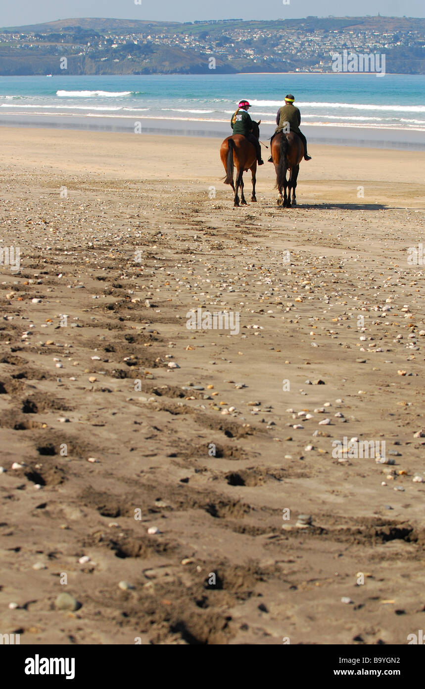 Un couple de cavaliers sur la plage de Gwithian, Cornwall, Angleterre Banque D'Images