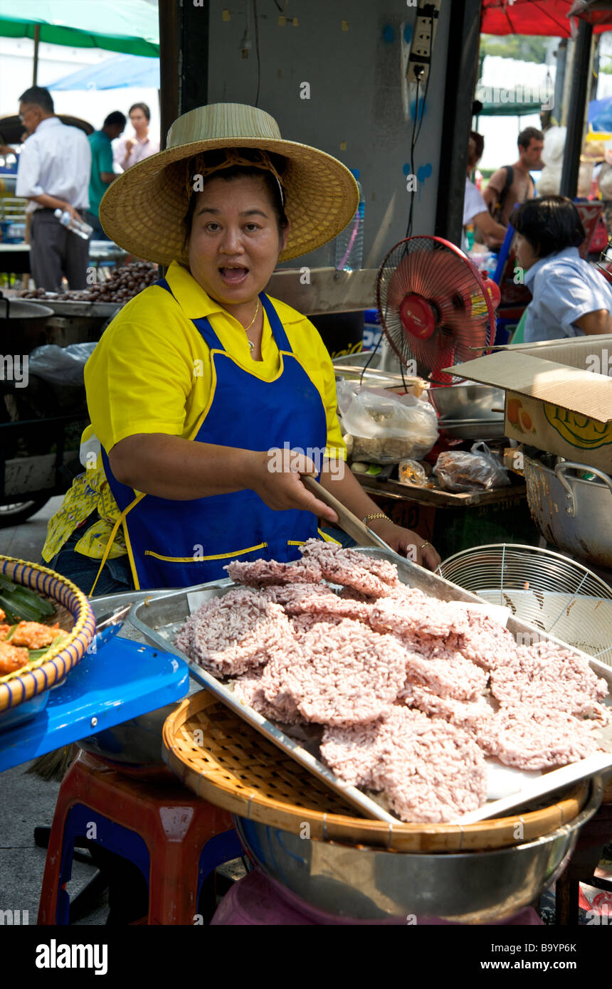 Une heureuse femme thaïlandaise frire des gâteaux de riz sur son stand de Bangkok Thaïlande Banque D'Images