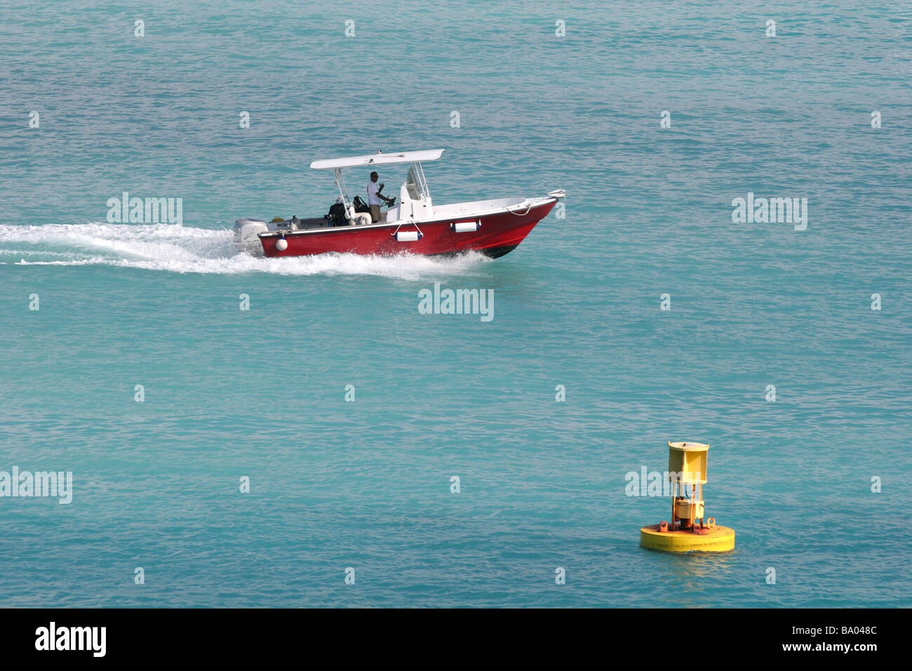 Rouge un bateau à moteur dans l'eau bleu avec une bouée jaune Banque D'Images