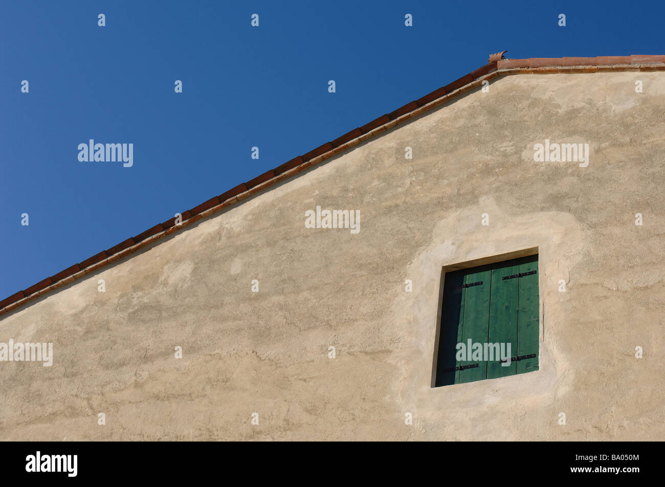 Le pignon d'un bâtiment de ferme avec des volets verts sur une fenêtre Banque D'Images