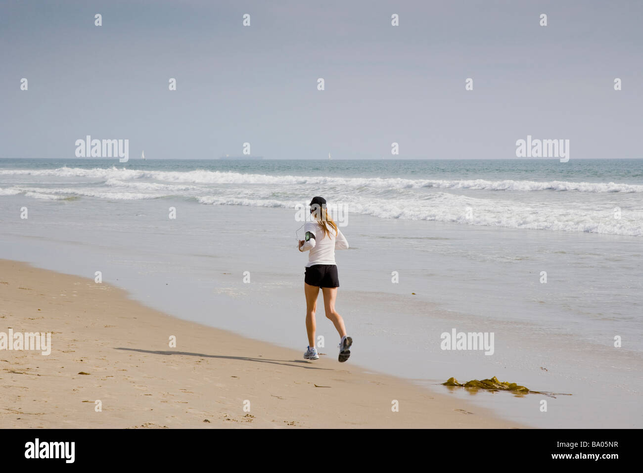 Jogger avec l'iPod sur la plage de Santa Monica Los Angeles California USA Banque D'Images
