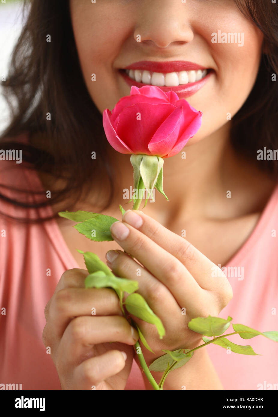 Woman smelling pink rose Banque D'Images