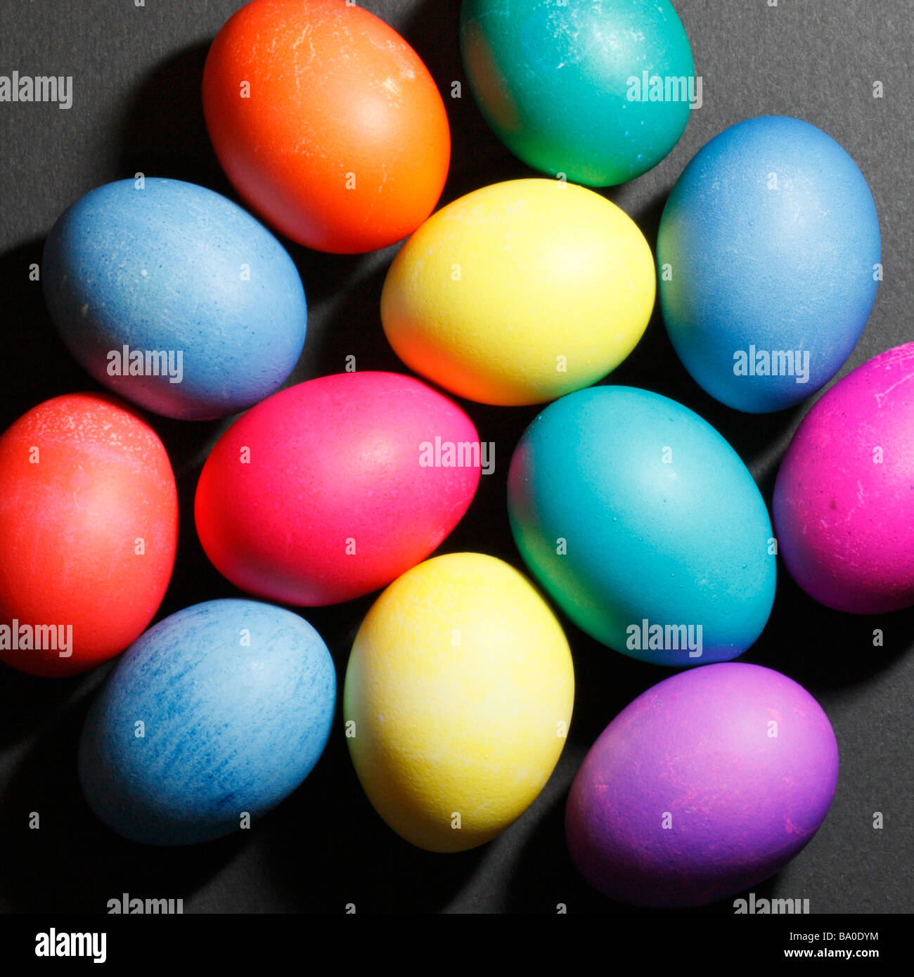 Une douzaine d'œufs de Pâques colorés sur fond noir. Banque D'Images